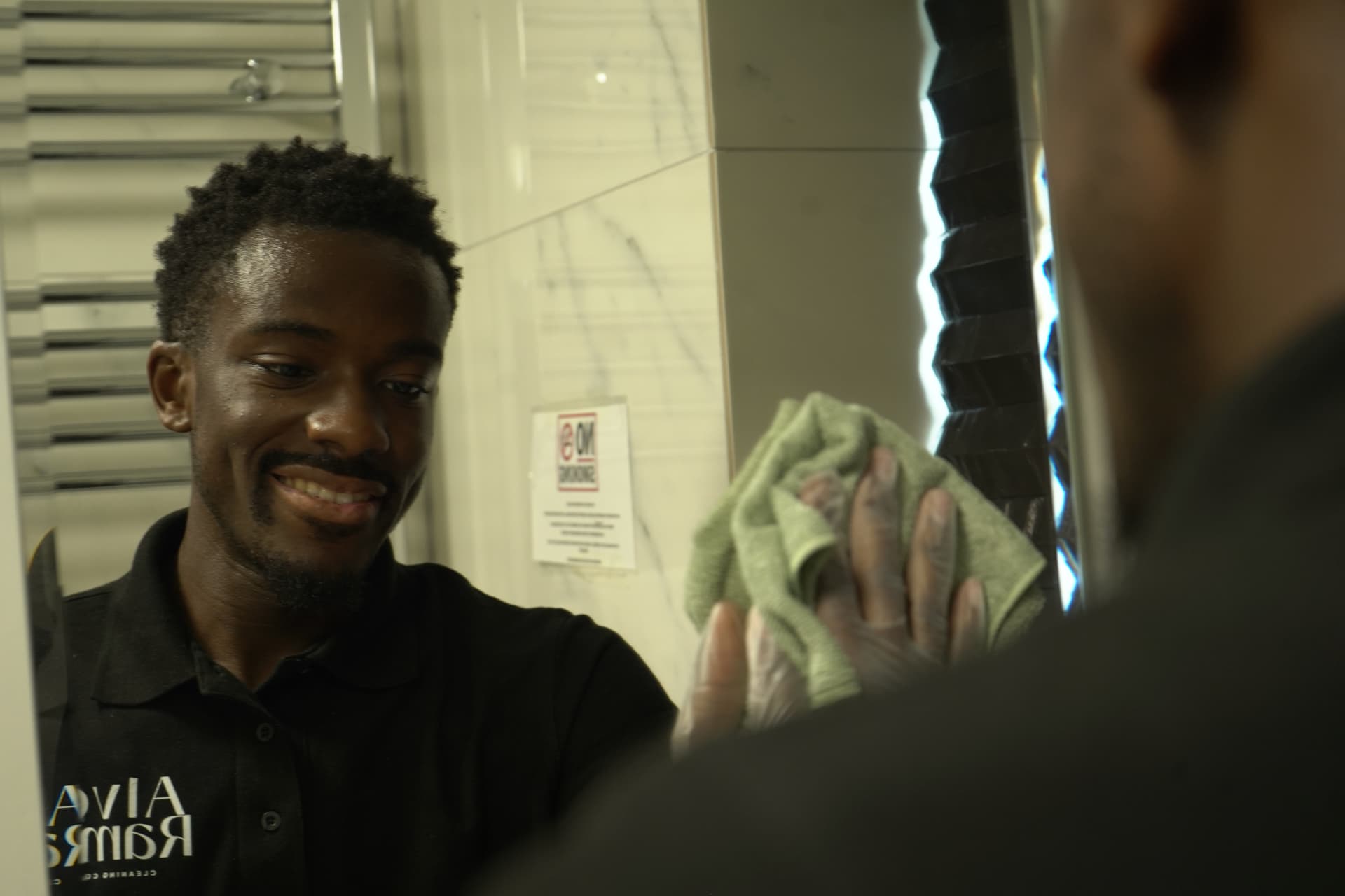 An Alves & Ramos cleaner polishing a bathroom mirror